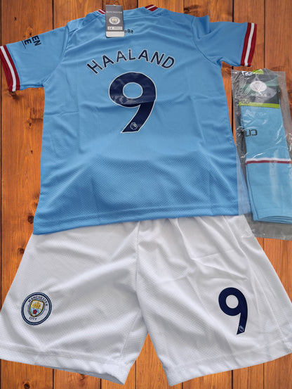 Tenue football Erling Haaland Manchester City avec maillot bleu ciel n°9 et short blanc assorti. Ensemble idéal pour jeunes joueurs passionnés.