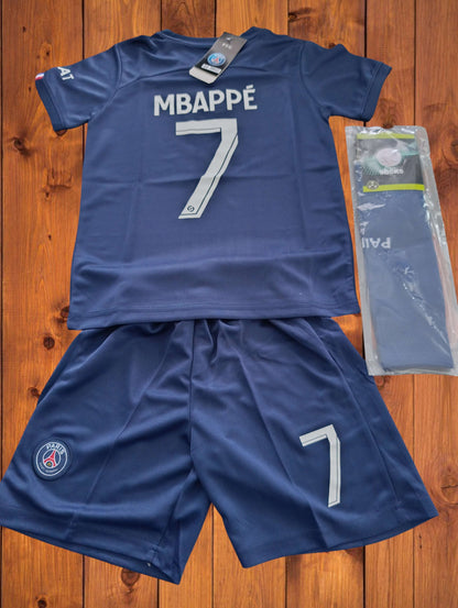 Tenue foot inspirée de Kylian Mbappé PSG avec t-shirt floqué Mbappé 7, short assorti et chaussettes, idéale pour jeunes fans du PSG.